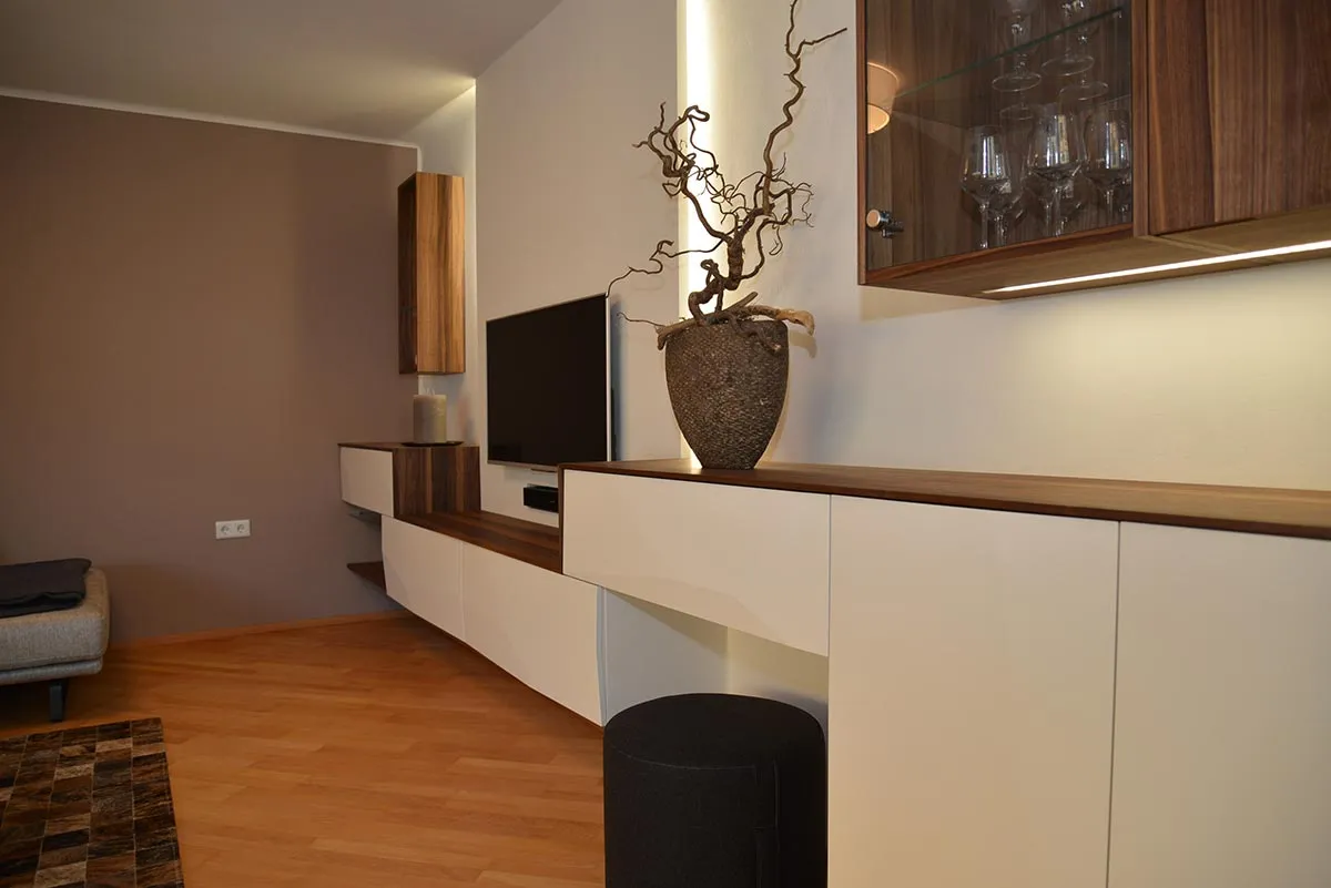 Wohnzimmer mit weißem Lowboard und beleuchtetem Hängeschrank
